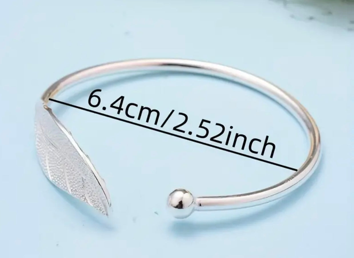 Pictured on a light blue background, the I AM ARTEMIS Wild One Leaf Bangle from Freya Canada. Image shows clearly the size of the bangle. Ships from Vancouver BC.