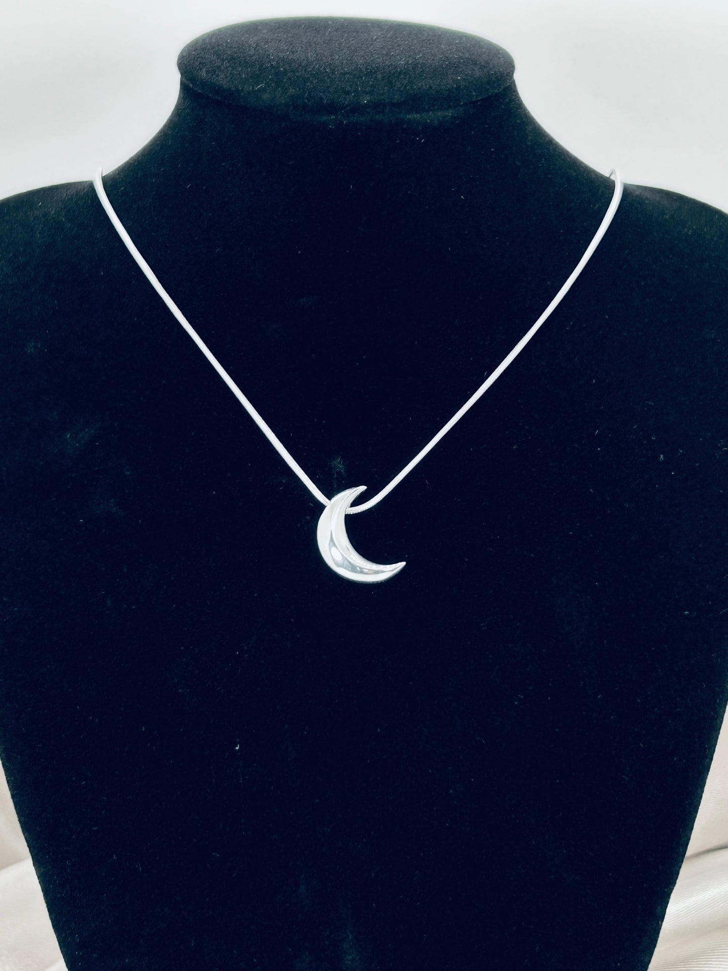 Freya Canada’s I AM SELENE sterling silver luminous crescent moon necklace. Close up, on a black jewelry bust display.