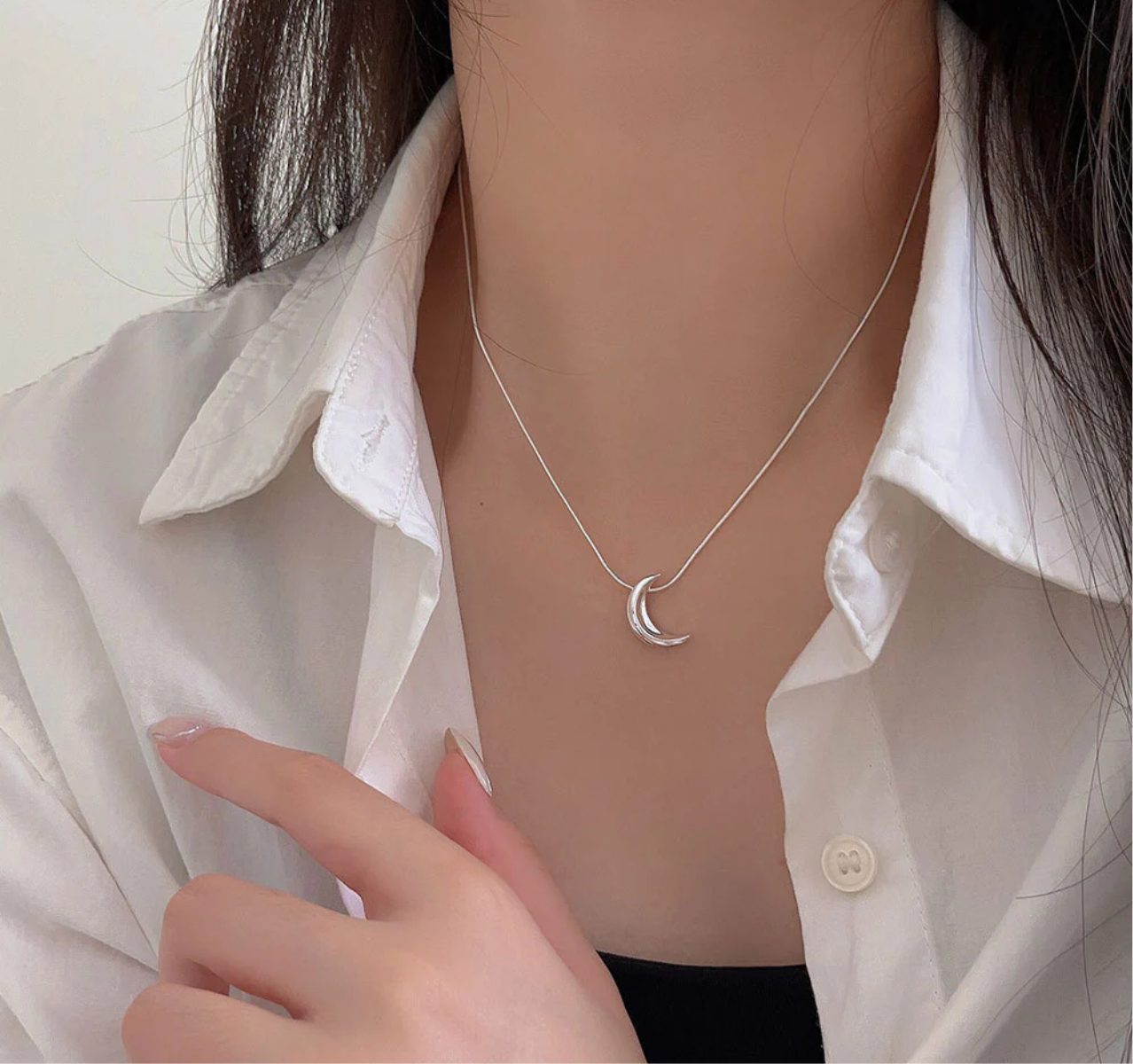 Model is wearing Freya Canada’s I AM SELENE sterling silver luminous crescent moon necklace. Close up of neck.