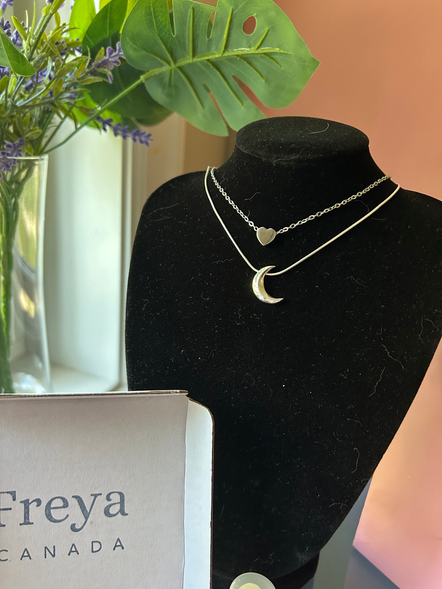 A few Freya Canada necklaces on a black jewelry bust display with Freya packaging