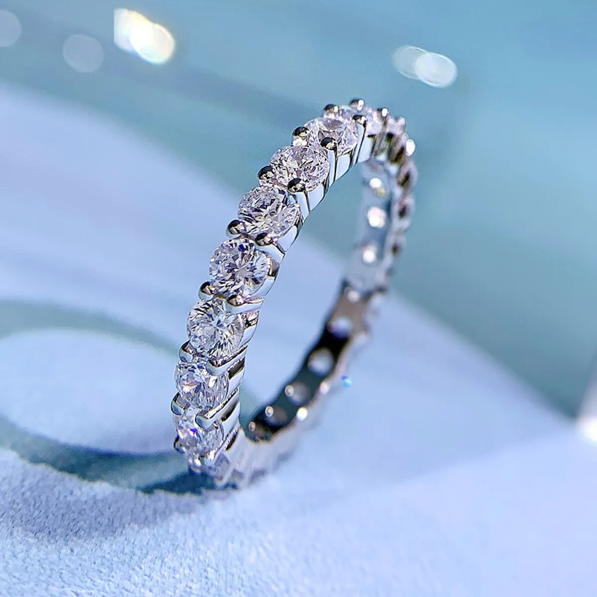 Freya Canada’s I AM ETERNITY Radiant zircon band ring, professional photography, displayed standing up on a blue background