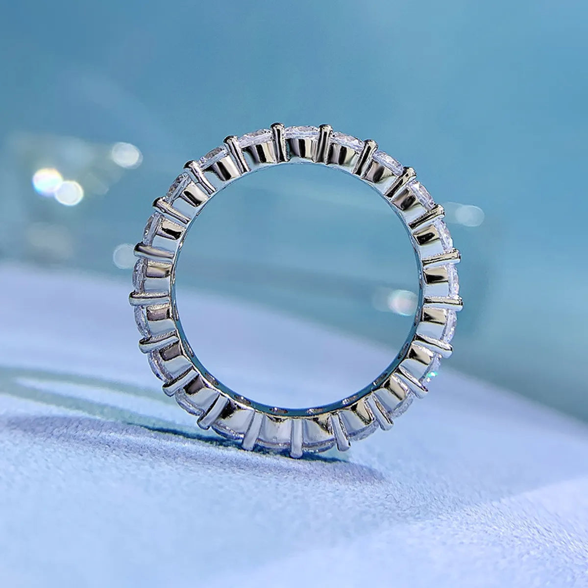 Freya Canada’s I AM ETERNITY Radiant zircon band ring, professional photography, displayed standing up on a blue background